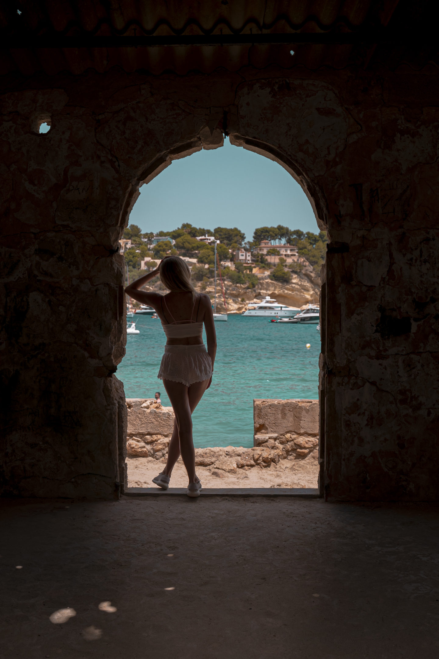 Girl leaning against building looking out over ocean