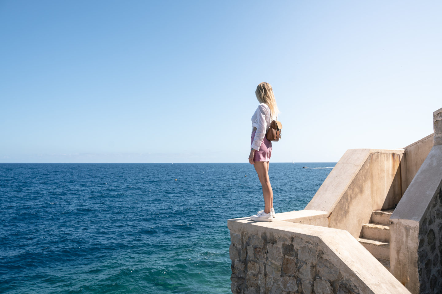 girl standing on wall looking at ocean